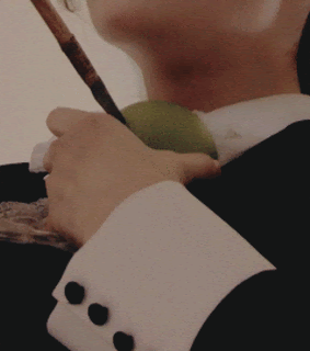 A gif of Chuu holding an arrow in a green apple as she falls backwards, heart-shaped red confetti shooting out in a flurry.